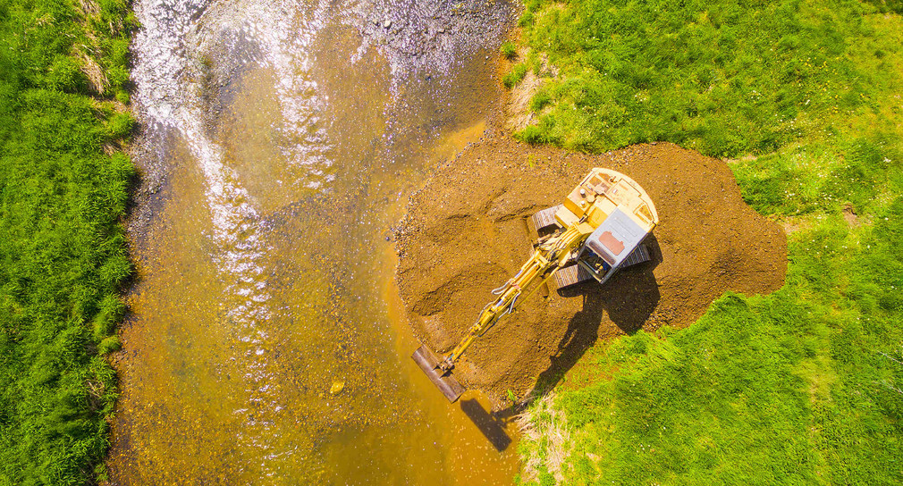 Luftaufnahme eines Baggers der auf goldenem Fluss gräbt