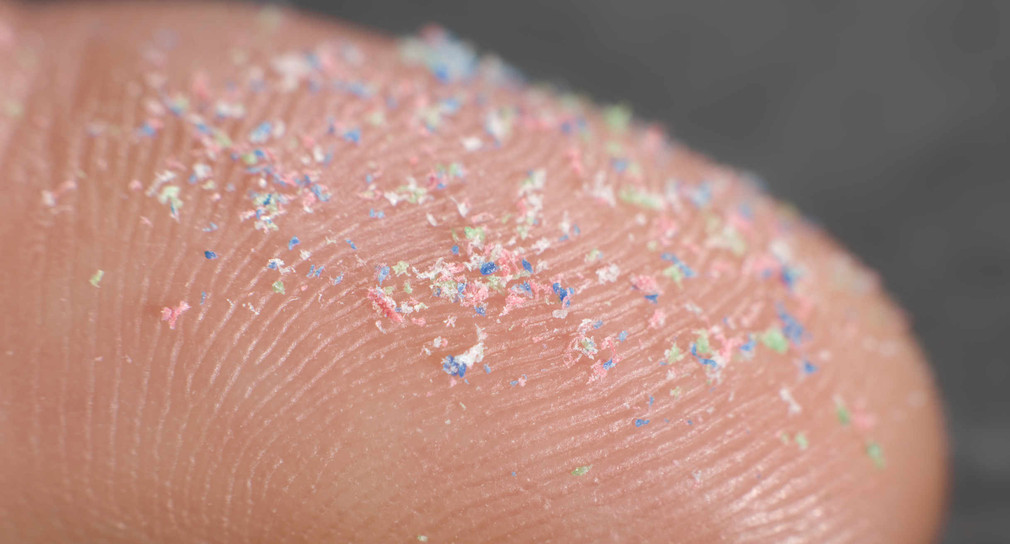 Kunststoff-Partikel, winzige Mikroplastik-Partikel auf Finger