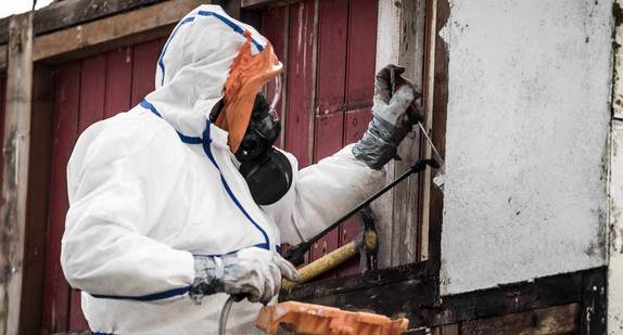 Arbeiter in Schutzkleidung beim Entfernen von asbesthaltigen Materialien