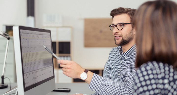 Geschäftsmann erklärt einer Kollegin etwas am Computer