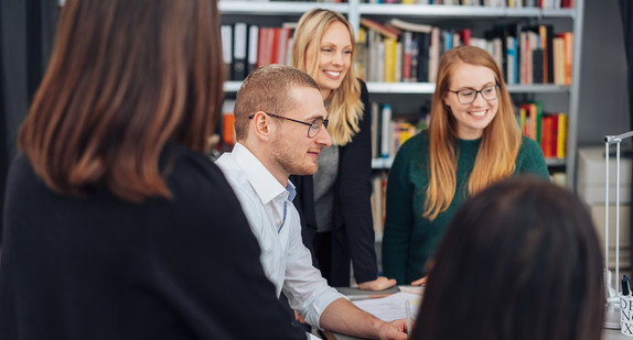 Eine Gruppe junger Menschen haben sich vor einem Computer versammelt