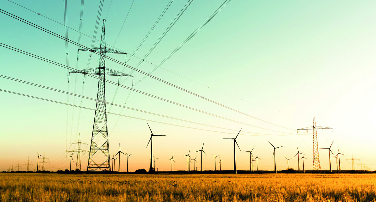 Strommasten, Kornfeld und Windräder im herbstlichen Gegenlicht