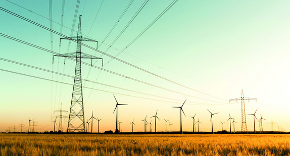 Strommasten, Kornfeld und Windräder im herbstlichen Gegenlicht
