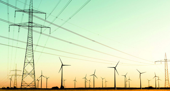 Strommasten, Kornfeld und Windräder im herbstlichen Gegenlicht