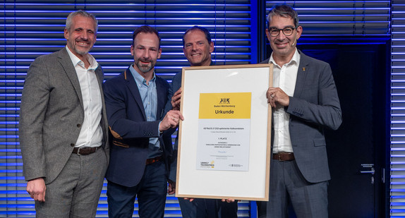 Der Umwelttechnikpreis 2025 geht an die E. Bayer Baustoffwerke GmbH & Co. KG. Staatssekretär Dr. Andre Baumann (rechts) überreichte die Urkunde.