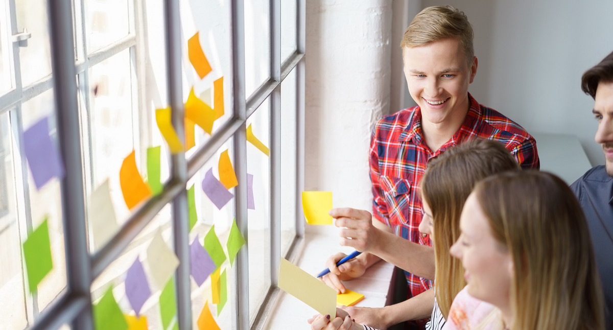 Mitarbeitende sammeln Ideen und kleben Zettel ans Fenster
