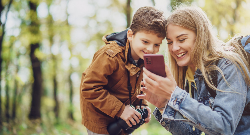 Mutter und Sohn wandern im Wald und verwenden Karten auf dem Smartphone