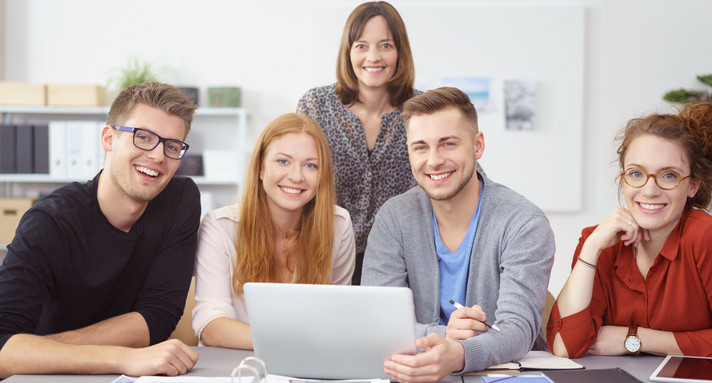 Im Büro: Junge Leute sitzen zusammen vor einem Notebook