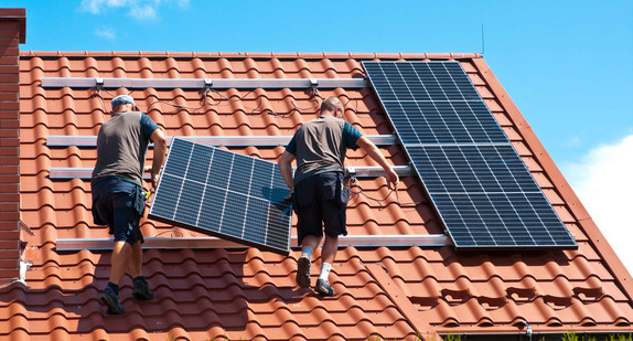 Handwerker installieren Sonnenkollektoren auf einem Hausdach