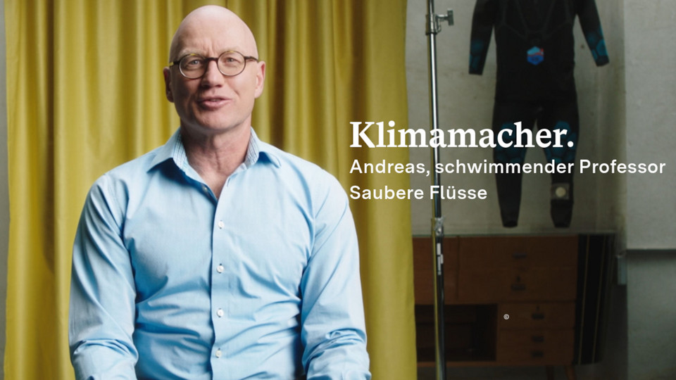 Andreas Fath schaut in die Kamera, im Hintergrund ist ein Vorhang und ein Tauchanzug zu sehen.