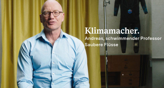 Andreas Fath schaut in die Kamera, im Hintergrund ist ein Vorhang und ein Tauchanzug zu sehen.