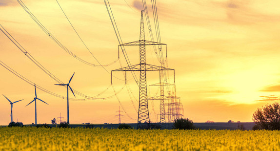 Strommasten und Windräder im Sonnenuntergang