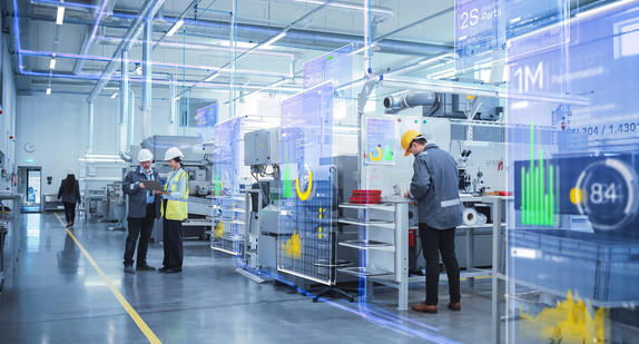 Moderne Produktionshalle mit Mitarbeitenden und digital vernetzten Fertigungsanlagen.