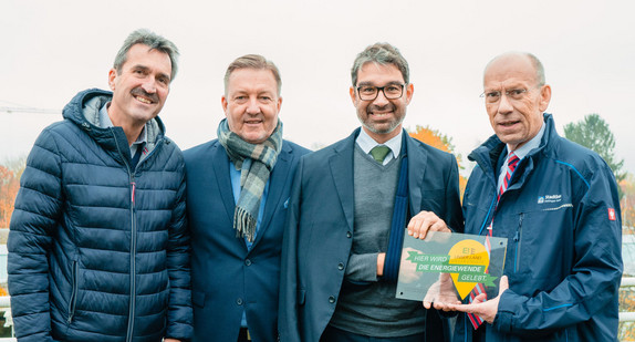 Umweltstaatssekretär Andre Baumann zeichnet die BürgerEnergiegenossenschaft Region Karlsruhe Ettlingen als „Ort voller Energie“ aus und überreicht Steffen Neumeister (Geschäftsführer der Stadtbau Ettlingen GmbH) die Plakette. Mit dabei (von links): Sven Scherer (Prokurist der Stadtwerke Ettlingen) und Thomas Müller (Vorstand der Baugemeinschaft Ettlingen eG).