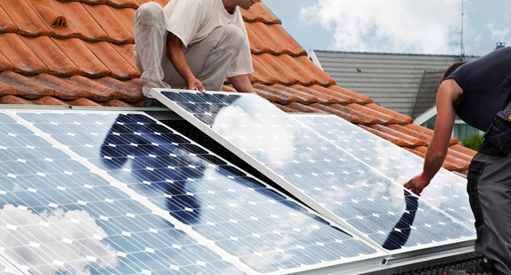 Handwerker verlegen Solarmodule auf einem Dach
