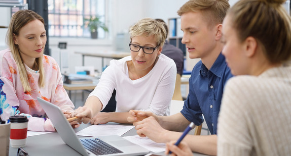 Geschäftsfrau erklärt jungen Kollegen etwas am Laptop