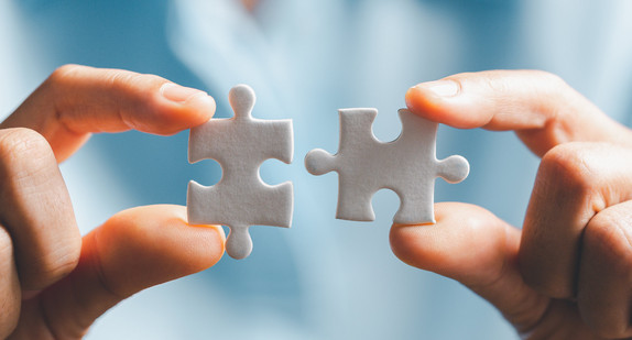 Nahaufnahme von zwei weißen Puzzleteilen, die sich verbinden