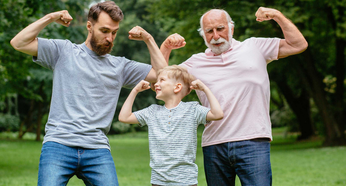 Drei Generationen im Park: Opa, Vater und Sohn zeigen lächelnd ihre Muskeln