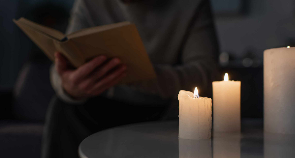 Mann liest bei Kerzenlicht