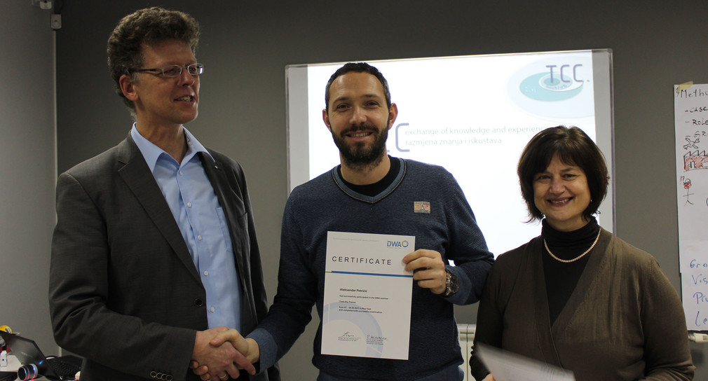 Coach Roland Knitschky from the German Association for Water Management, Wastewater and Waste (l.) and Dr. Heike Burghard, Managing Director TCC Danubius, (r.) congratulate Aleksandar Petričić on his successful training as a TCC coach.