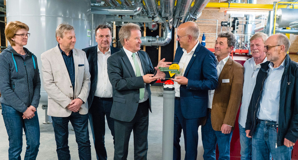 Minister Franz Untersteller (4. von links) hat das Nahwärmenetz Ilsfeld als „Ort voller Energie“ ausgezeichnet und Bürgermeister Thomas Knödler (5. von links) die Plakette überreicht. 