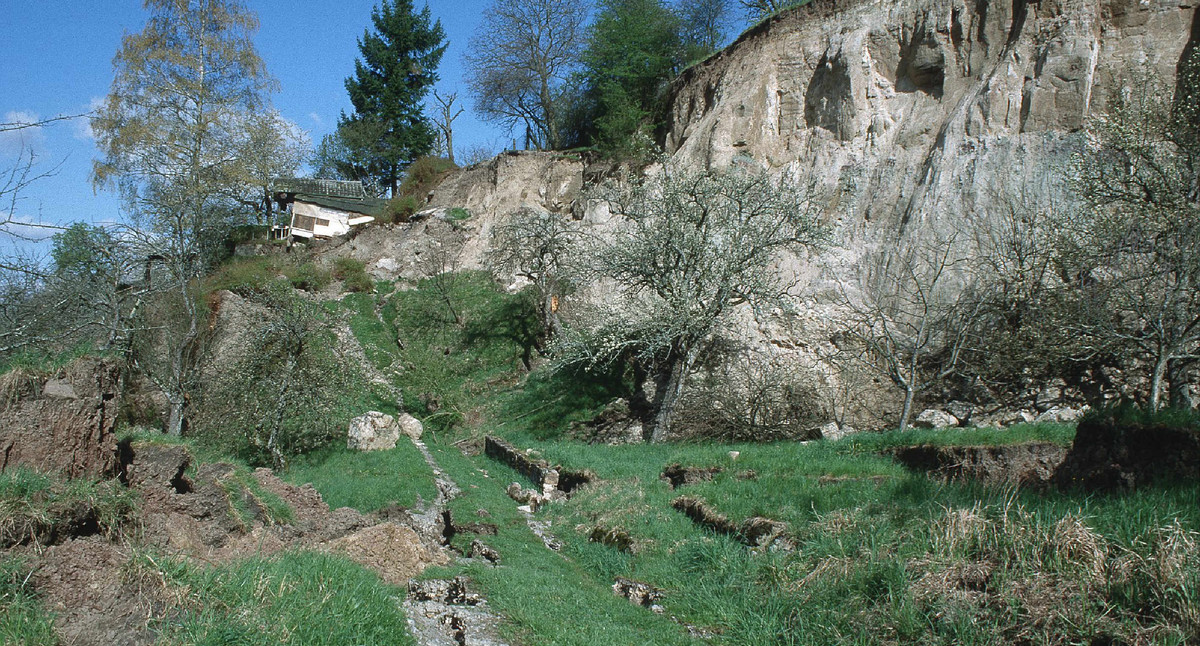 Rutschmassentop der Rutschung im Kirchsteigtobel bei Urbach mit Abrisskante und angrenzenden Hütten, Blickrichtung Nordwest