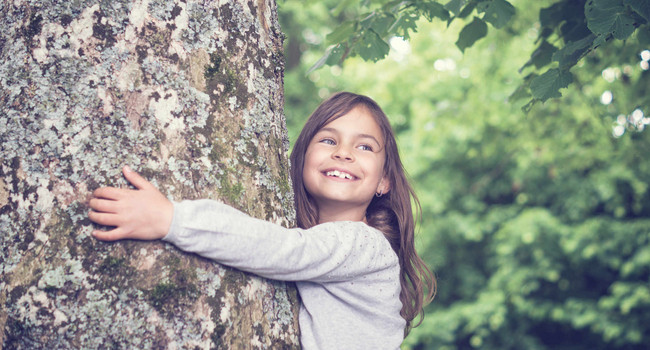 Mädchen umarmt einen Baum
