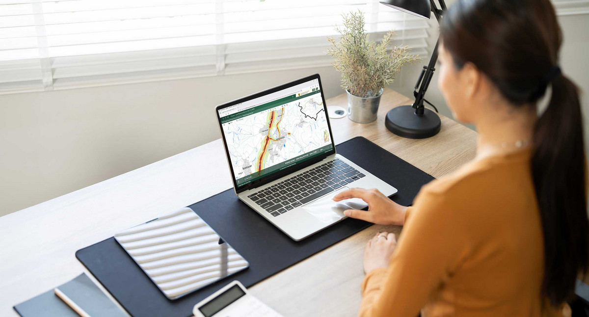 junge Frau sitzt am Laptop und bedient den Daten- und Kartendienst der LUBW