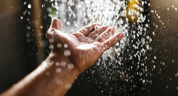 Hand eines Mannes unter Wasserstrahl