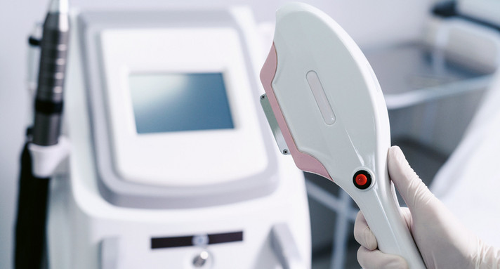 Kosmetikerin hält ein Gerät zur Laser-Haarentfernung