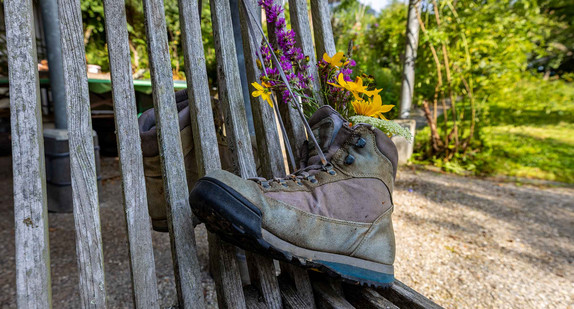 Wanderschuh befestigt an einem Holzzaun