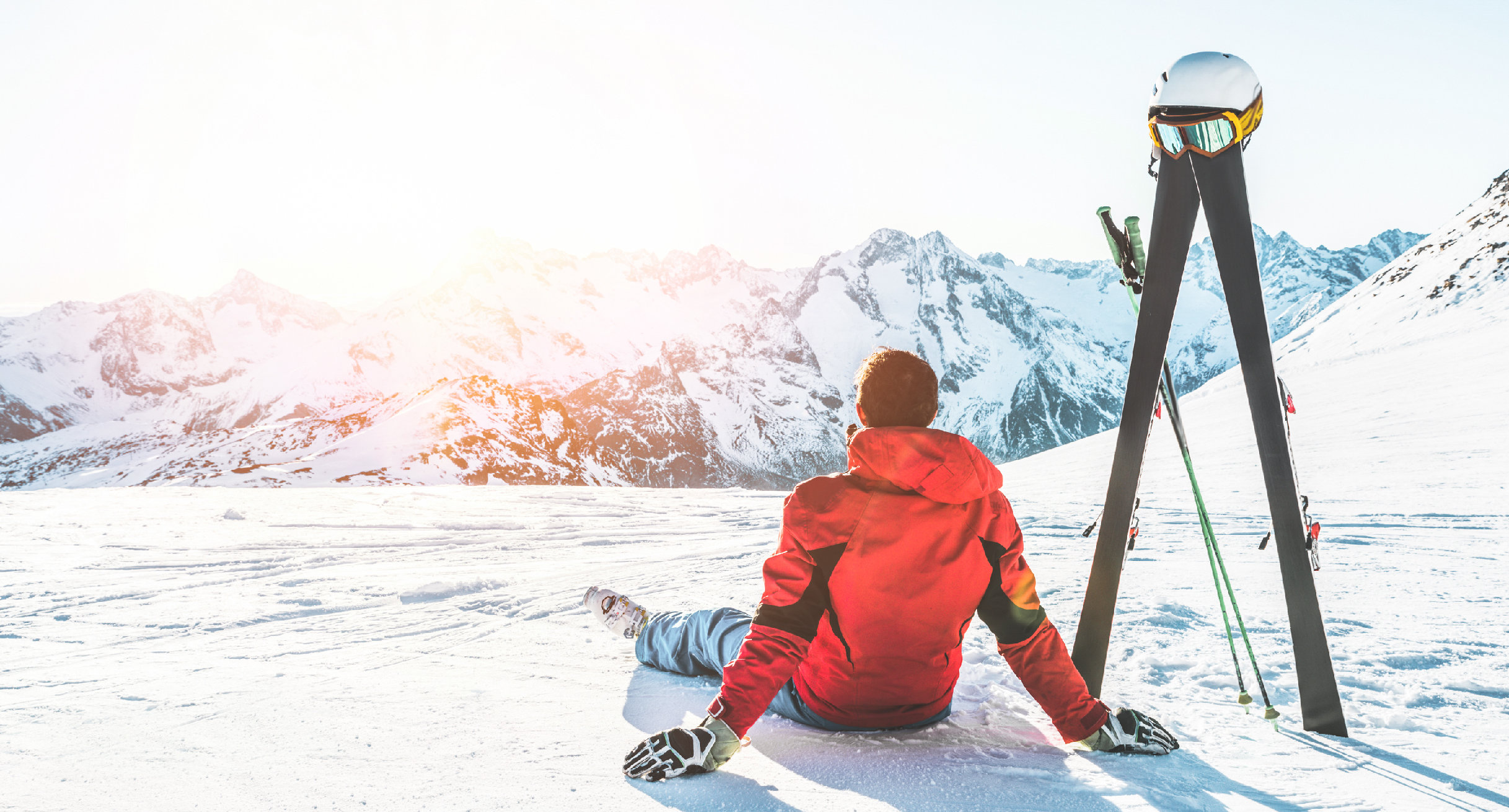 Skifahrer sitzt auf einem Berg und macht Pause