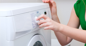 Frau stellt Waschmaschine an